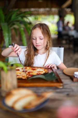 Adorable little girl eating pizza for lunchの写真素材