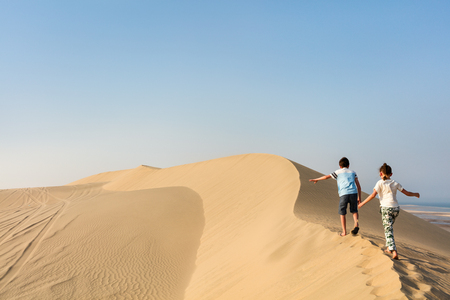 Kids having fun playing together at sand dunes in Qatar desertの写真素材
