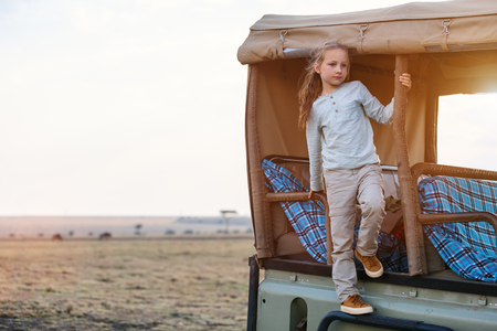 Adorable little girl in Kenya safari on morning game drive in open vehicleの写真素材