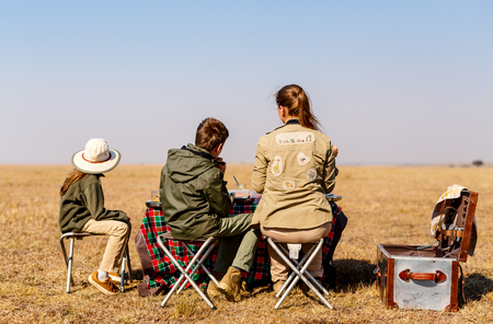 Back view family of mother and kids on African safari vacation enjoying bush breakfastの写真素材