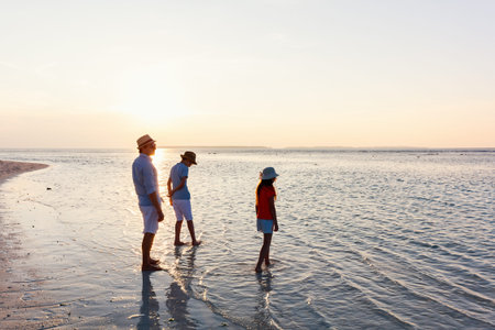 Father and kids at sunset enjoying beach vacation on tropical island