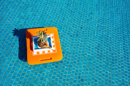 Tropical cocktail in pineapple shell floating at poolの写真素材