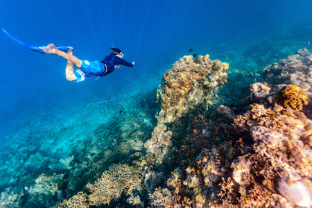 Underwater photo of a young man snorkeling free diving at coral reef in tropical oceanの写真素材