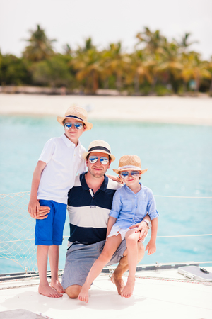 Happy father and his adorable kids outdoors sailing on yacht or catamaranの写真素材
