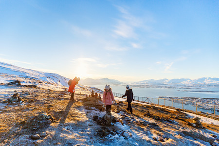 Beautiful family of mother and kids have a pleasant time on snowy winter day outdoors enjoying views near Tromso Norwayの写真素材