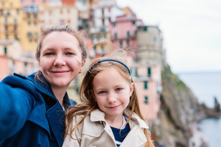 Mother and daughter taking selfie at scenic view of colorful village in Cinque Terre, Italy on backgroundの写真素材