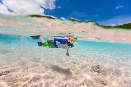 Split of above and underwater photo of cute little boy swimming in oceanの写真素材