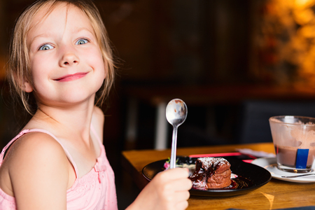 Casual portrait of adorable little girl enjoying meal at restaurantの写真素材