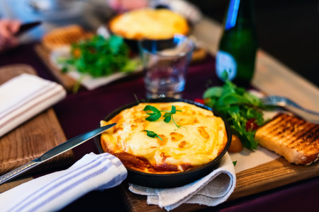 Delicious breakfast with omelet served in frying pan in restaurantの写真素材