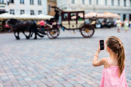 Back view of adorable girl outdoors exploring Tallinn old town on summer dayの写真素材