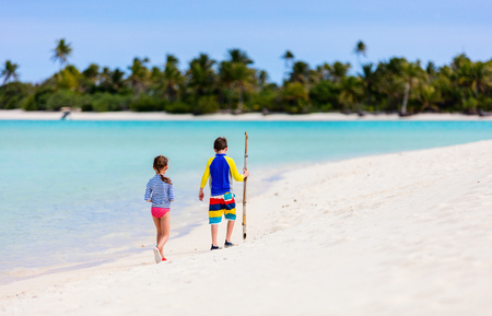 Little kids in rash guards for sun protection on tropical beach during summer vacationの写真素材