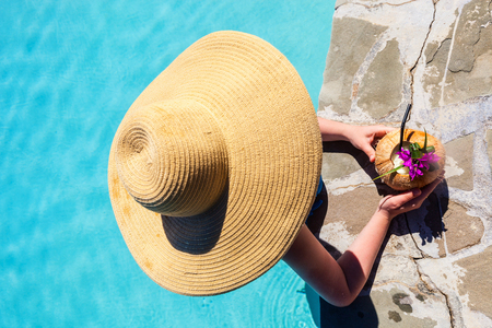 Top view of girl relaxing in swimming pool with tropical drinkの写真素材