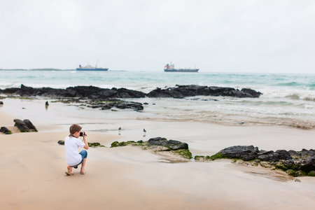 Little boy at beach with volcanic lava rock formations on Galapagos islandsの写真素材