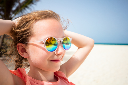Adorable little girl at beach during summer vacation wearing sunglasses reflecting tropical beach with palm treesの写真素材