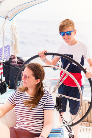 Family of mother and son on board of sailing yacht having summer travel adventureの写真素材