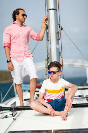 Father and his teenager son on board of sailing yacht having summer travel adventureの写真素材