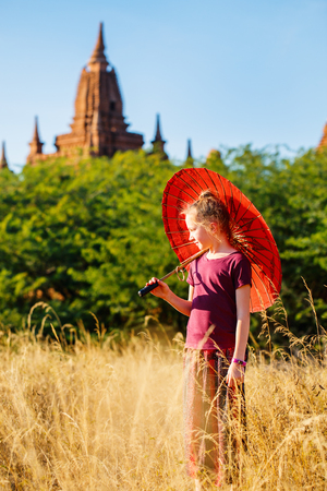 Young girl with traditional burmese parasol visiting ancient temples in Bagan Myanmarの写真素材