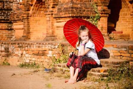 Young girl with traditional burmese parasol visiting ancient temples in Bagan Myanmarの写真素材