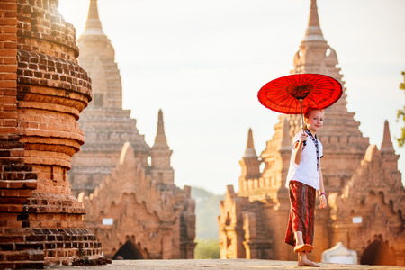 Young girl with traditional burmese parasol visiting ancient temples in Bagan Myanmar at sunsetの写真素材
