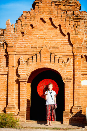 Young girl with traditional burmese parasol visiting ancient temples in Bagan Myanmarの写真素材