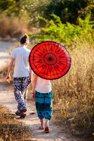 Back view of teenage boy and young girl with traditional burmese parasol outdoorsの写真素材