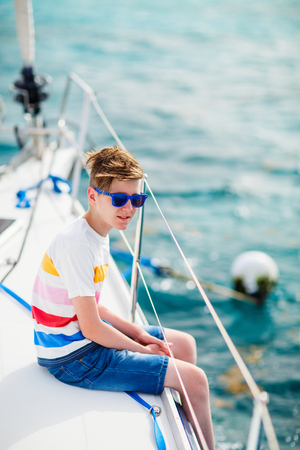 Teenage boy enjoying sailing on board a chartered catamaran or yachtの写真素材