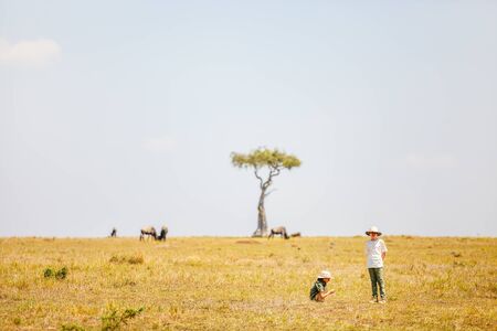Kids witnessing great migration of wildebeests in Masai Mara National park in Kenyaの写真素材