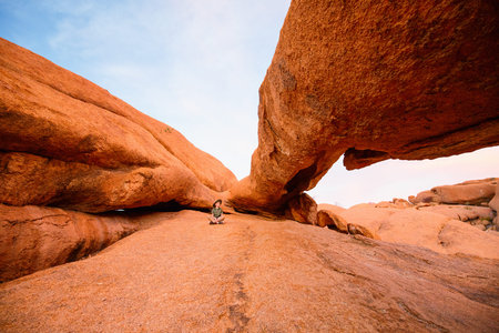 Young girl in Spitzkoppe area with picturesque stone arches and unique rock formations in Damaraland...