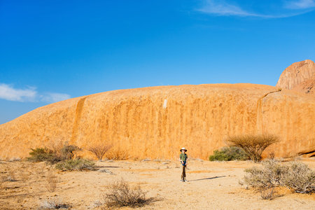 Young girl in Spitzkoppe area with picturesque stone arches and unique rock formations in Damaraland...
