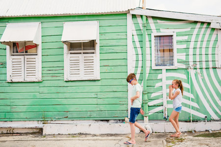Two kids boy and girl outdoors against colorful house on Barbados island in Caribbean