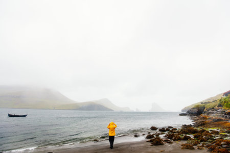 Back view of young woman at beach enjoying breathtaking scenery of Faroe islands