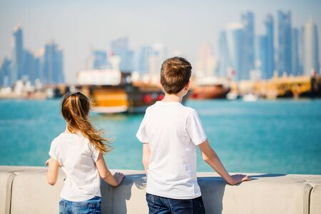 Kids brother and sister enjoying panoramic view of Doha Qatar skyline on sunny dayの写真素材