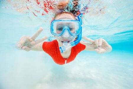 Underwater photo of a little girl swimming and snorkeling in tropical oceanの写真素材
