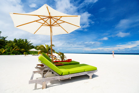 Wooden lounge chairs on a beautiful tropical beach at Maldives