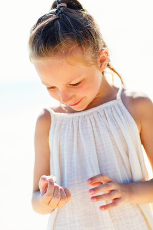 Adorable little girl holding tiny crab at beach during summer vacationの写真素材