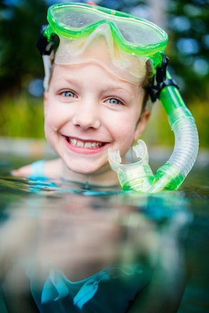 Adorable little girl with snorkeling equipment in a water during summer vacationの写真素材
