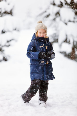 Adorable little girl wearing warm clothes outdoors on beautiful winter snowy day