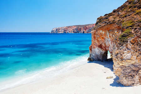Idyllic beach surrounded by beautiful cliffs dotted with sea caves on Greek island of Milosの写真素材