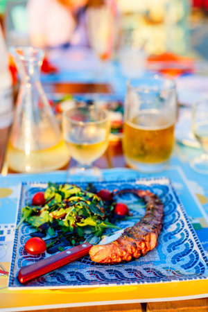 Delicious grilled octopus served with fresh vegetables and white wine for lunch or dinner in...