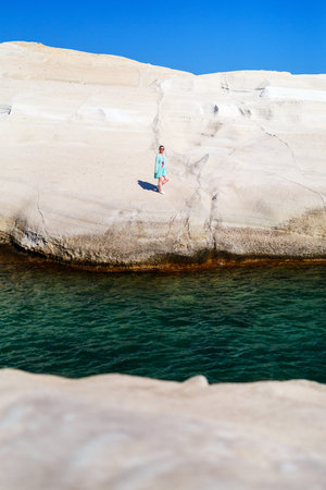 Attractive young woman walking on the lunar like landscape of Sarakiniko volcanic rock formations on island of Milos in Greeceの写真素材