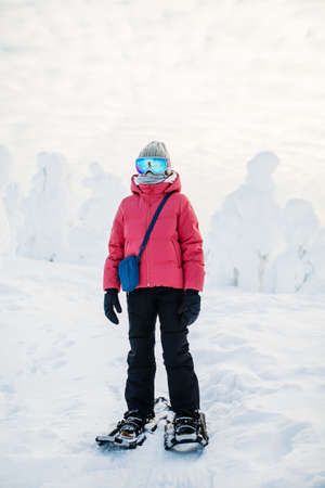 Cute pre-teen girl hiking in snowshoes in winter forest among snow covered trees in Lapland Finlandの写真素材