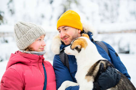 Family of father and his adorable pre-teen daughter cuddling with husky puppy outdoors on winter day in Lapland Finlandの写真素材