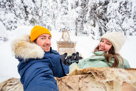 Happy couple on reindeer safari in winter forest in Lapland Finlandの写真素材