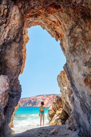 Cute teen girl enjoying breathtaking beach dotted with amazing sea caves on Greek island of Milosの写真素材