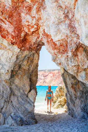 Cute teen girl enjoying breathtaking beach dotted with amazing sea caves on Greek island of Milosの写真素材