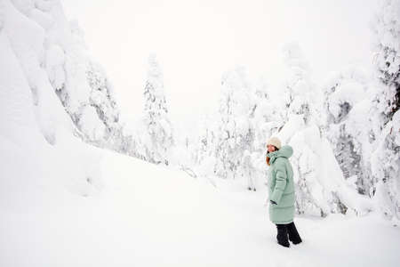 Young woman walking in winter forest among snow covered trees in Lapland Finlandの写真素材