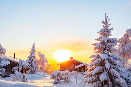 Beautiful winter landscape with wooden hut and snow covered trees at sunset in Lapland Finlandの写真素材