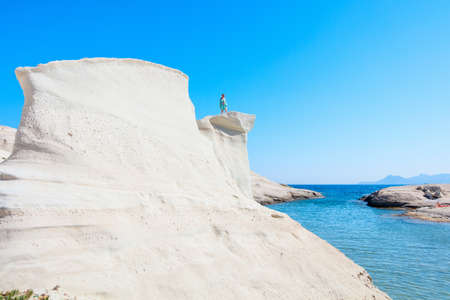 Attractive young woman walking on the lunar like landscape of Sarakiniko volcanic rock formations on island of Milos in Greeceの写真素材