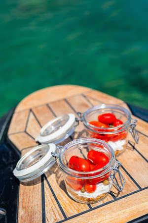Fresh delicious lunch salad with tomatoes and Greek cheese served on boat tour in Milos Greeceの写真素材