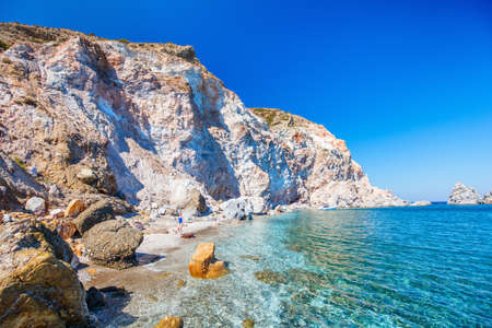 Young girl walking on idyllic beach surrounded by amazing cliffs on Greek island of Milosの写真素材